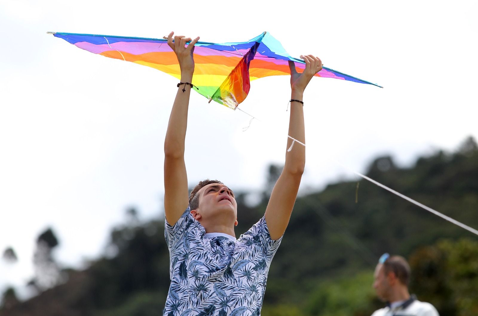 Joven sosteniendo una cometa con sus brazos estirados por encima de su cabeza