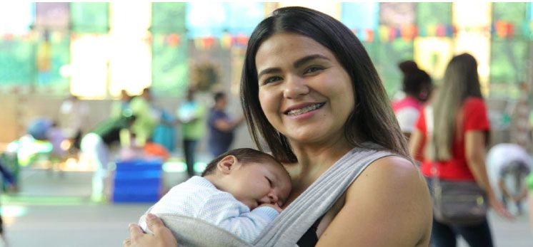 Mujer con su bebé en sus brazos, participando en las clases de Estimulación ofrecidas por el INDER