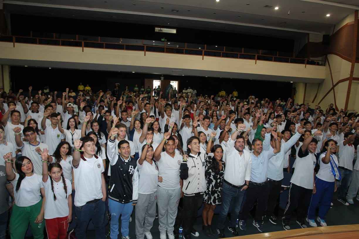 Estudiantes de una institución educativa de pie en un auditorio 